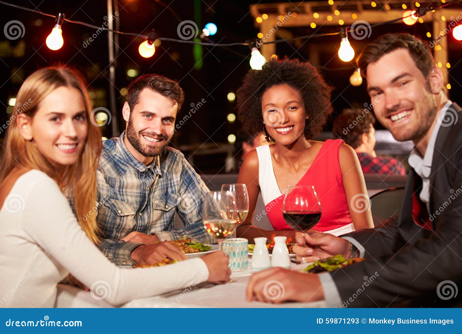 Four Friends Eating Dinner At Rooftop Restaurant Stock Image - Image of