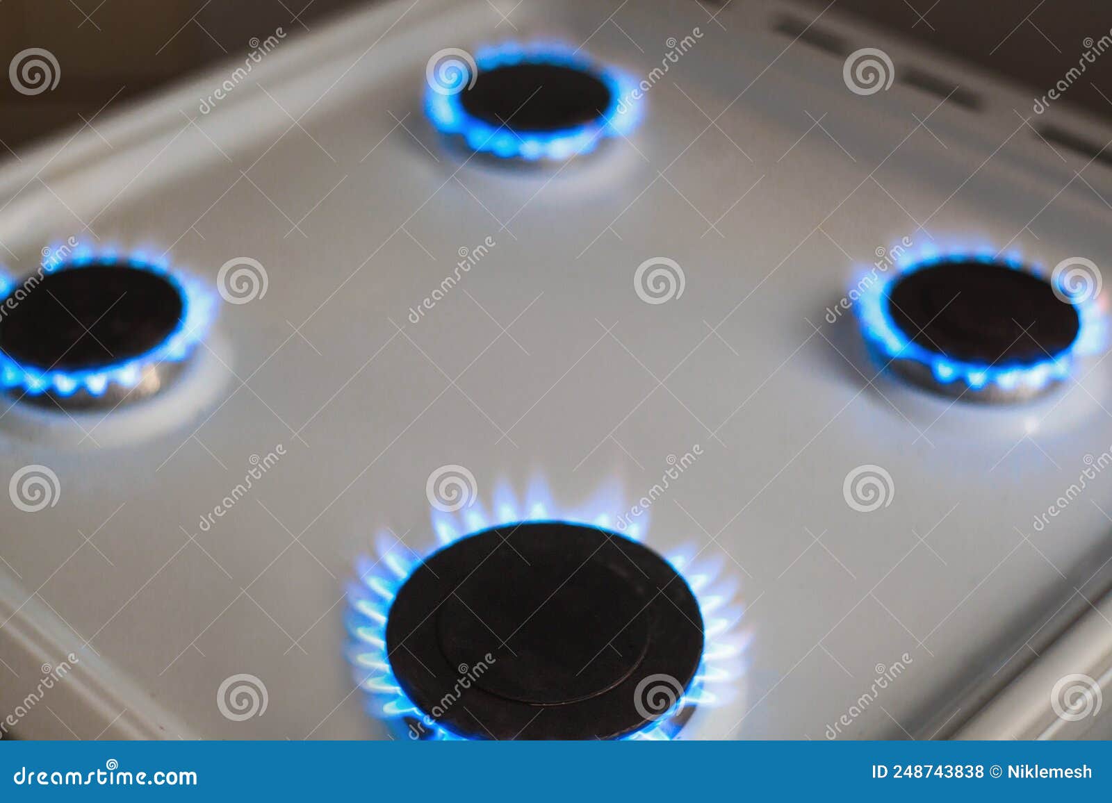 Four Gas Burners Burn with Blue Flames on a White Kitchen Stove Stock