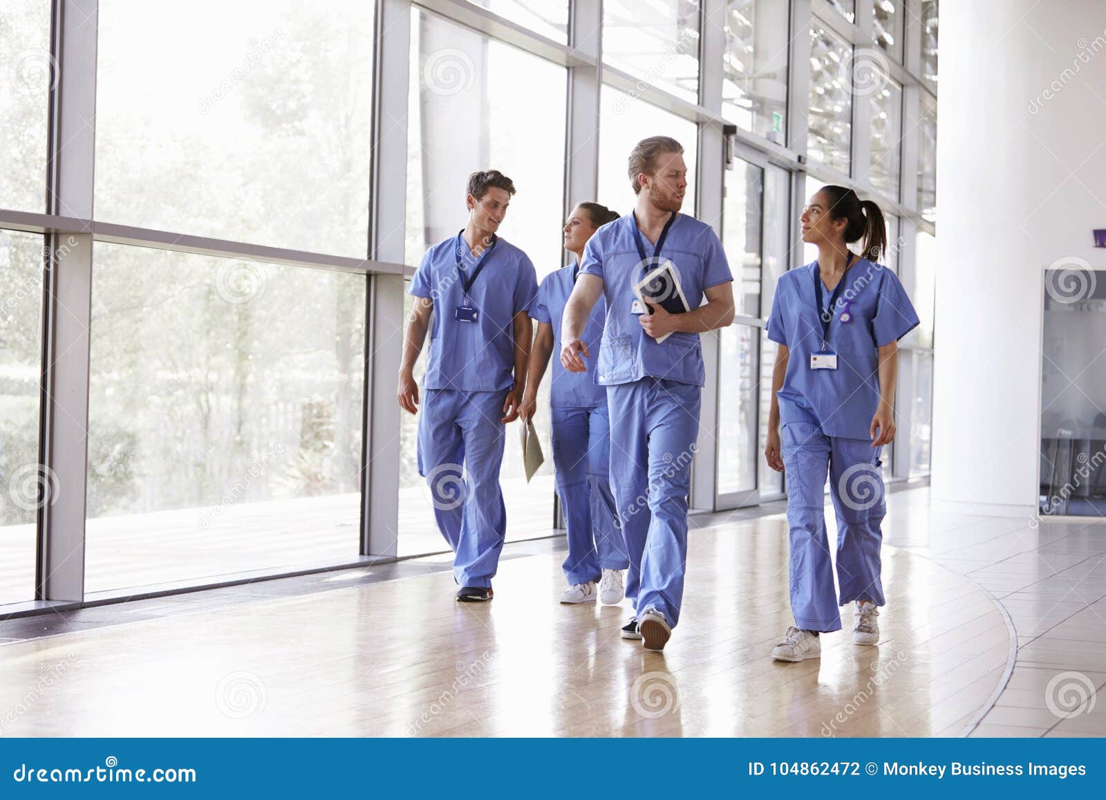 four healthcare workers in scrubs walking in corridor