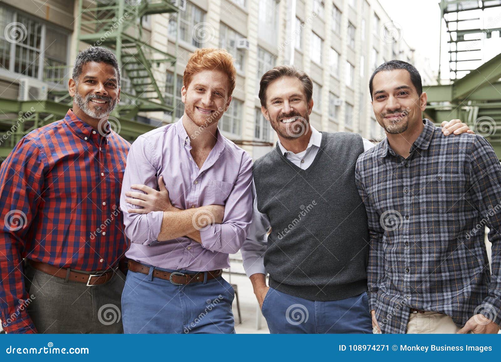 four male coworkers smiling to camera outside