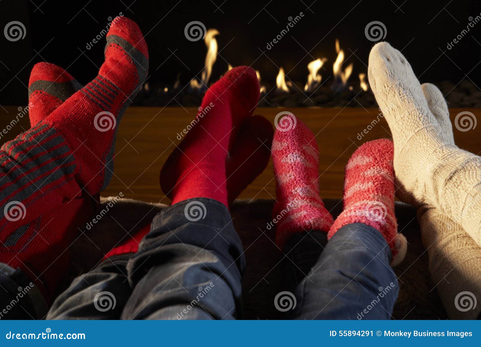 four pairs feet in socks warming by fire
