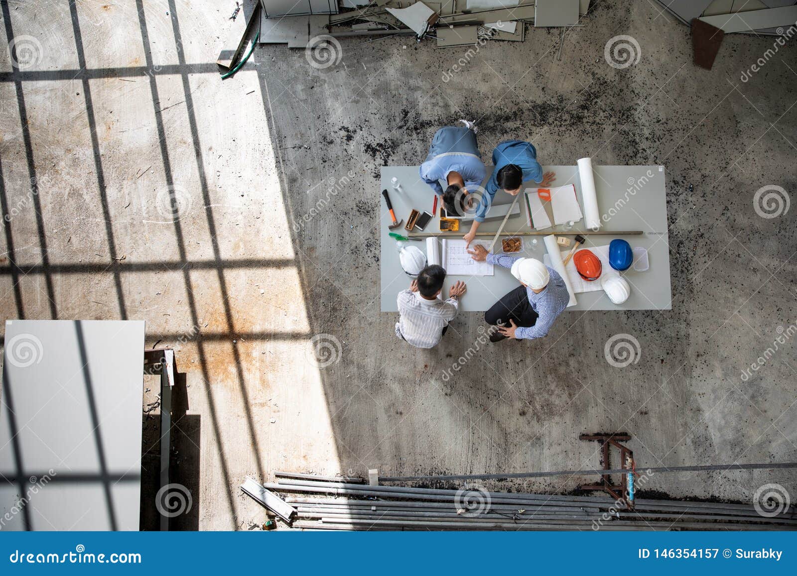 four persons team of engineers talk together to review constuction material and brainstorm about details of project