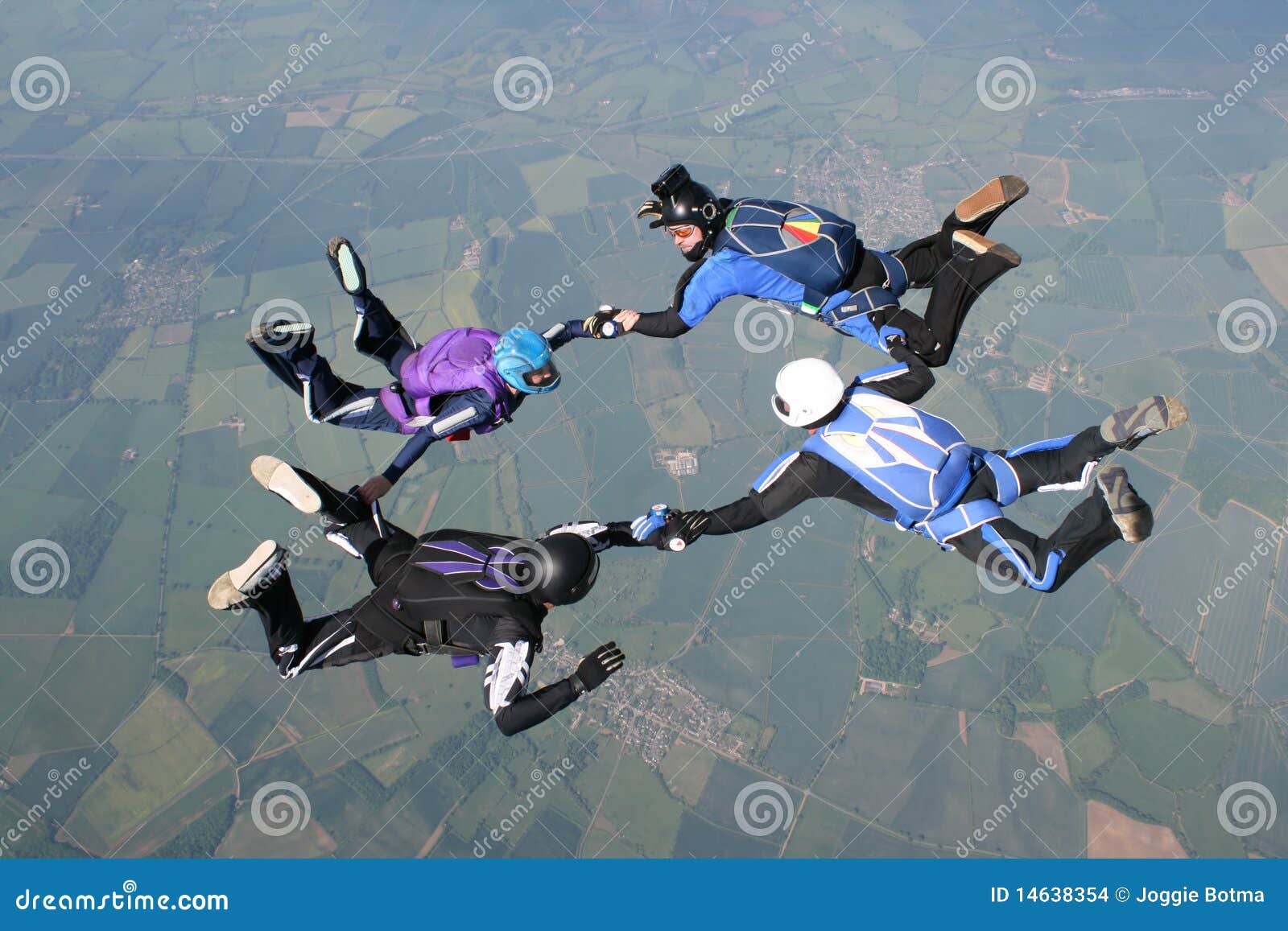 four skydivers holding hands