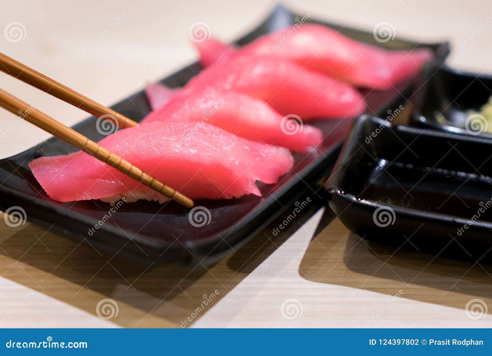 four tuna sushi with chopsticks in black plate on table at japanese restuarant.