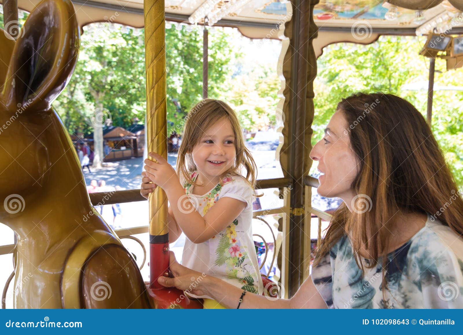 little girl in carousel smiling and looking at mother
