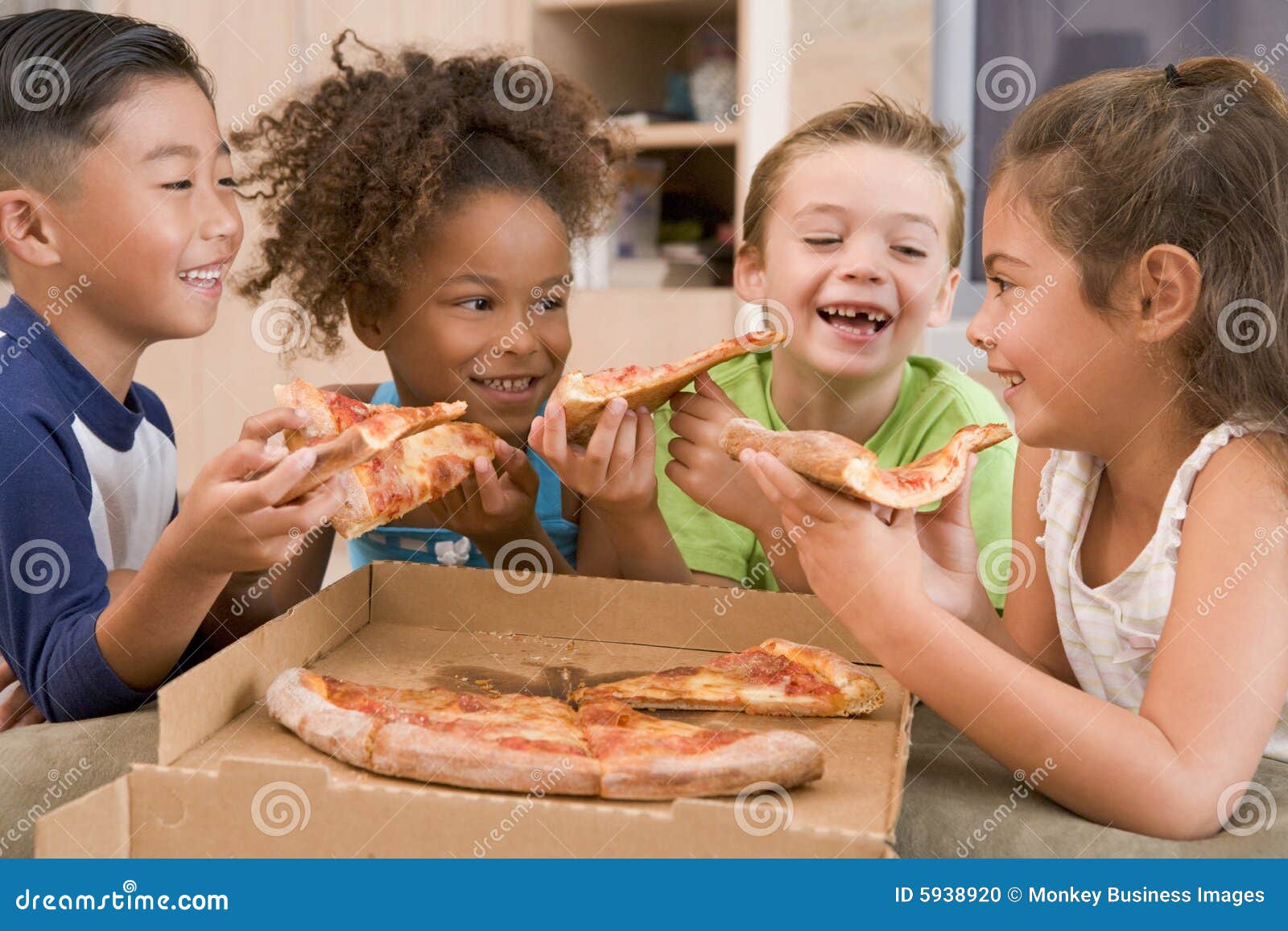 four young children indoors eating pizza