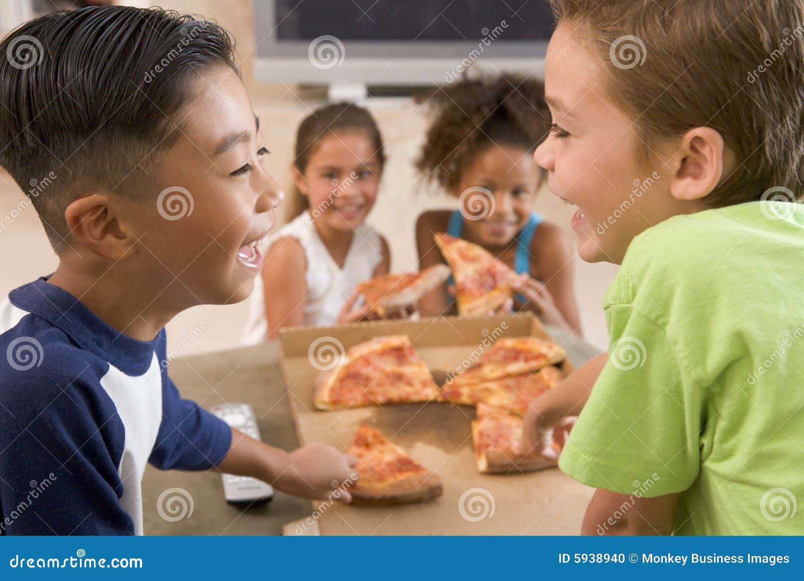 four young children indoors eating pizza