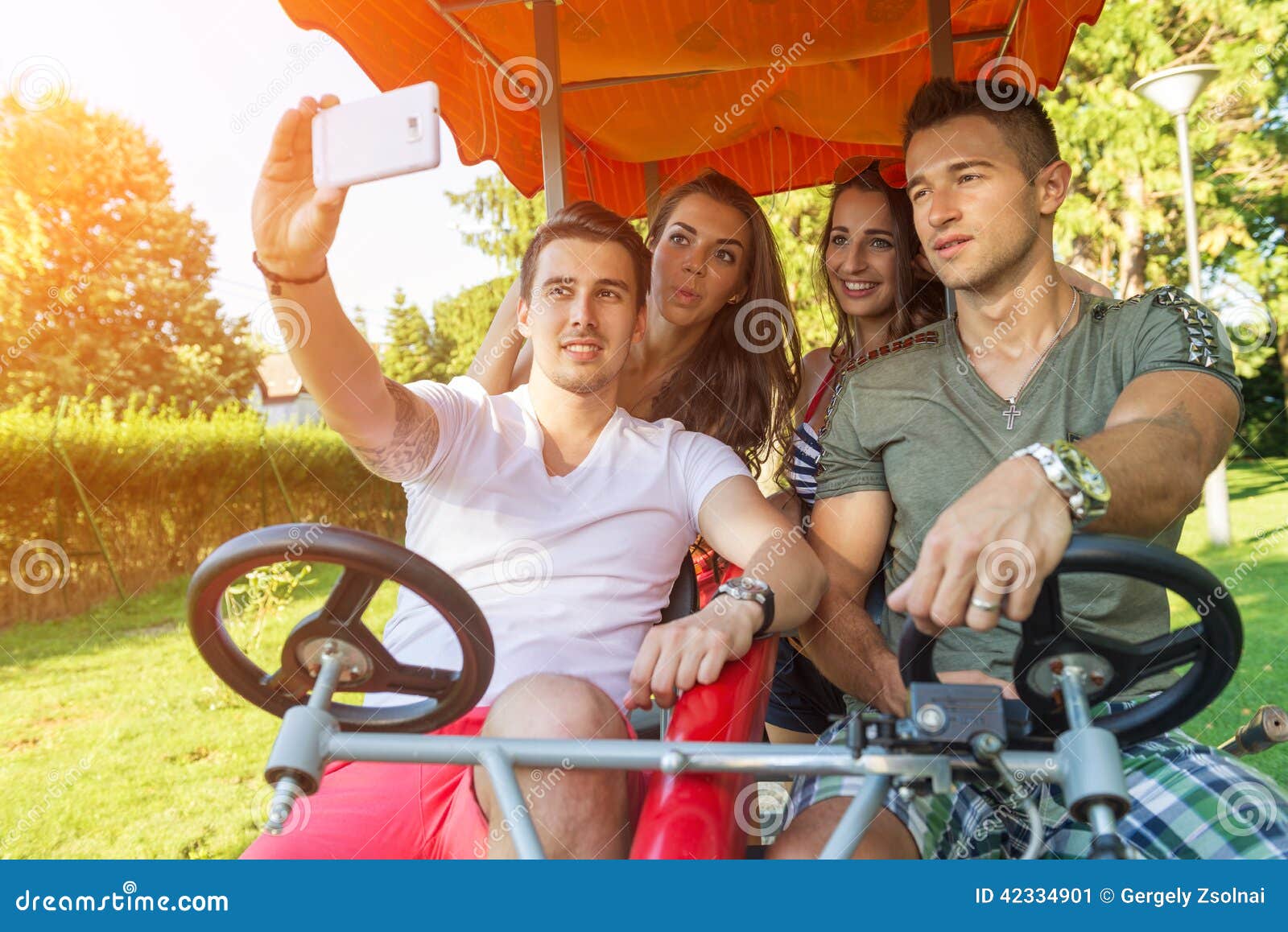 four young people in a four-wheeled bicycle, they do selfie
