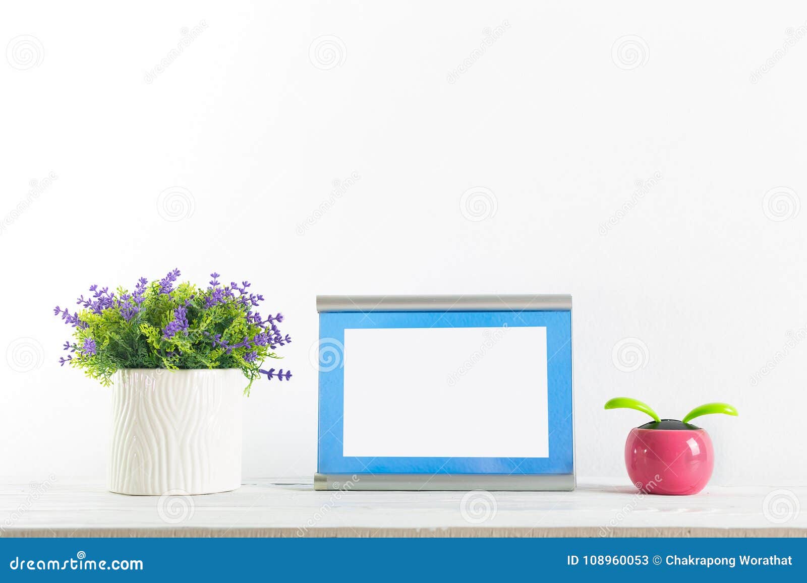 fowers and blue frame on a white with wall shelf.