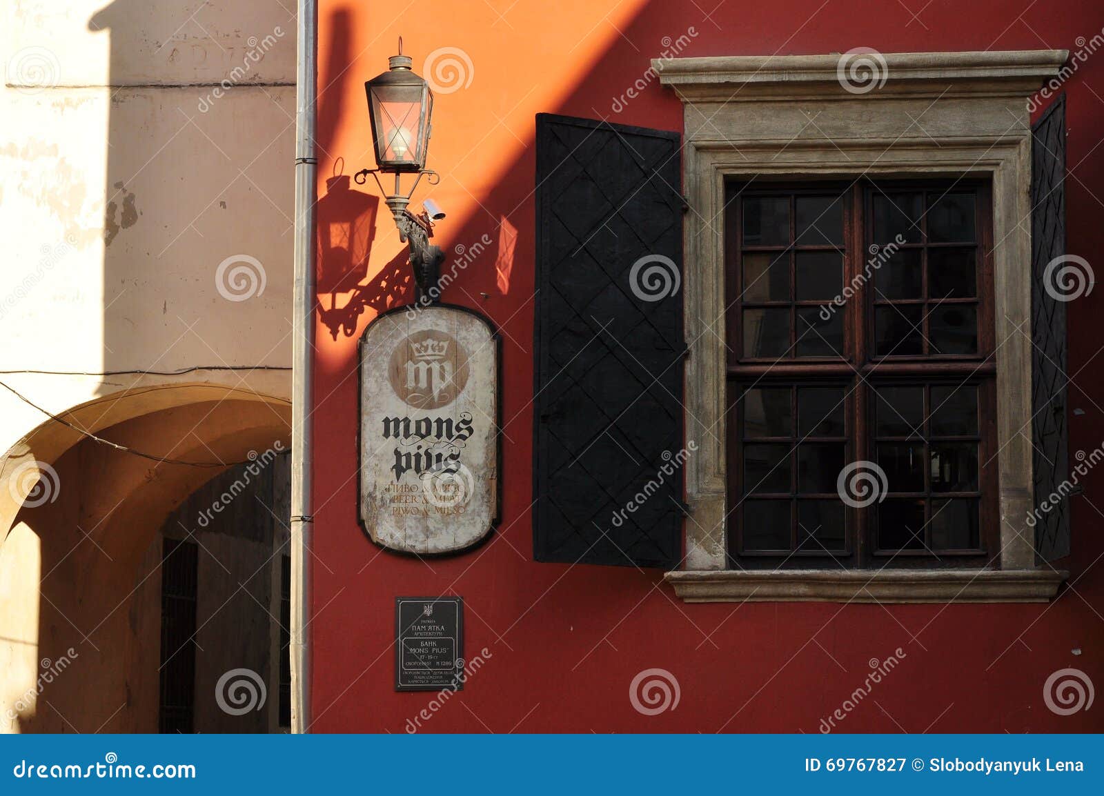 Fragment der alten Wand mit Fenster und Laterne. Fragment der alten Wand mit einem Fenster mit Metallfensterläden und eine Laterne, ein Licht und ein Schatten Lemberg, Ukraine