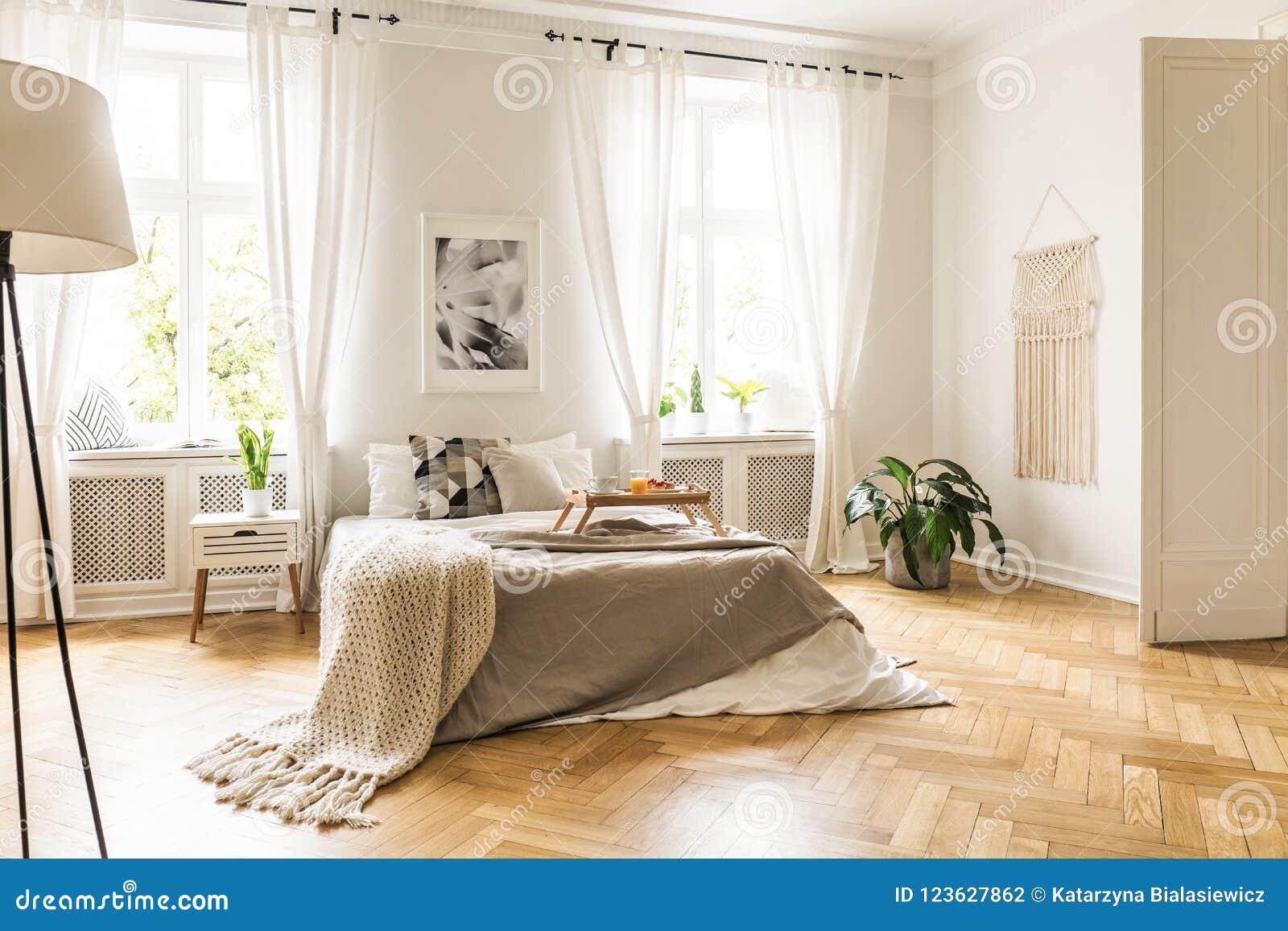 framed poster on a white wall above a cozy double bed with beige