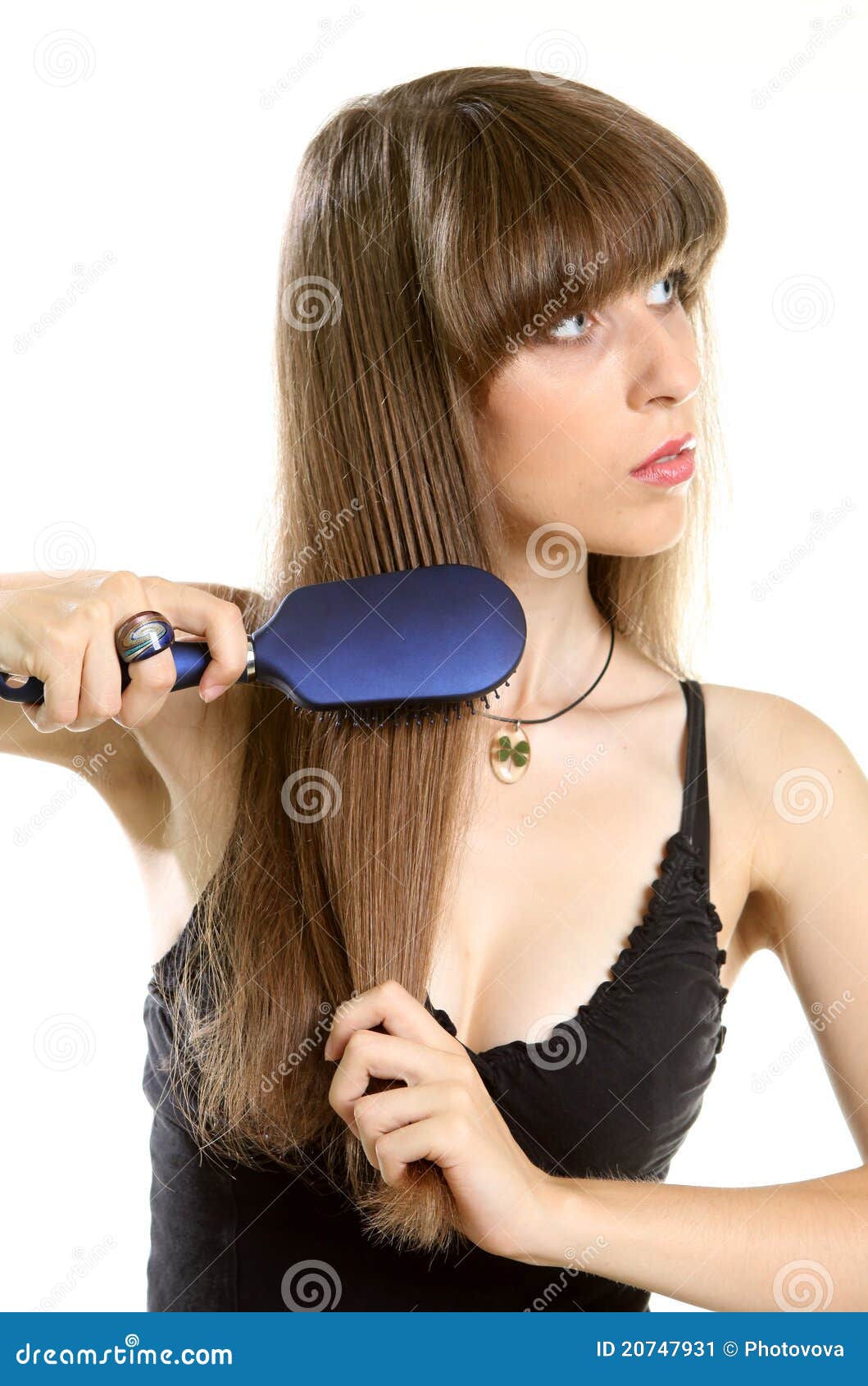 Frau, die ihr langes Haar mit Hairbrush kämmt. Lächelnde schöne junge Frau, die ihr langes braunes Haar mit dem Hairbrush - getrennt kämmt