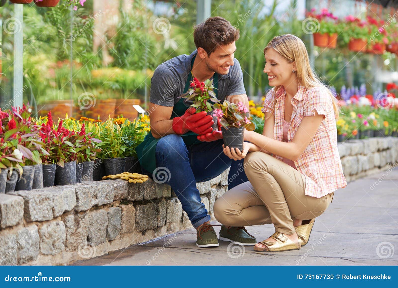 Frau, die mit Gärtner in Garten-Center spricht. Lächelnde Frauen, die mit Gärtner in Garten-Center über verschiedene Blumen sprechen