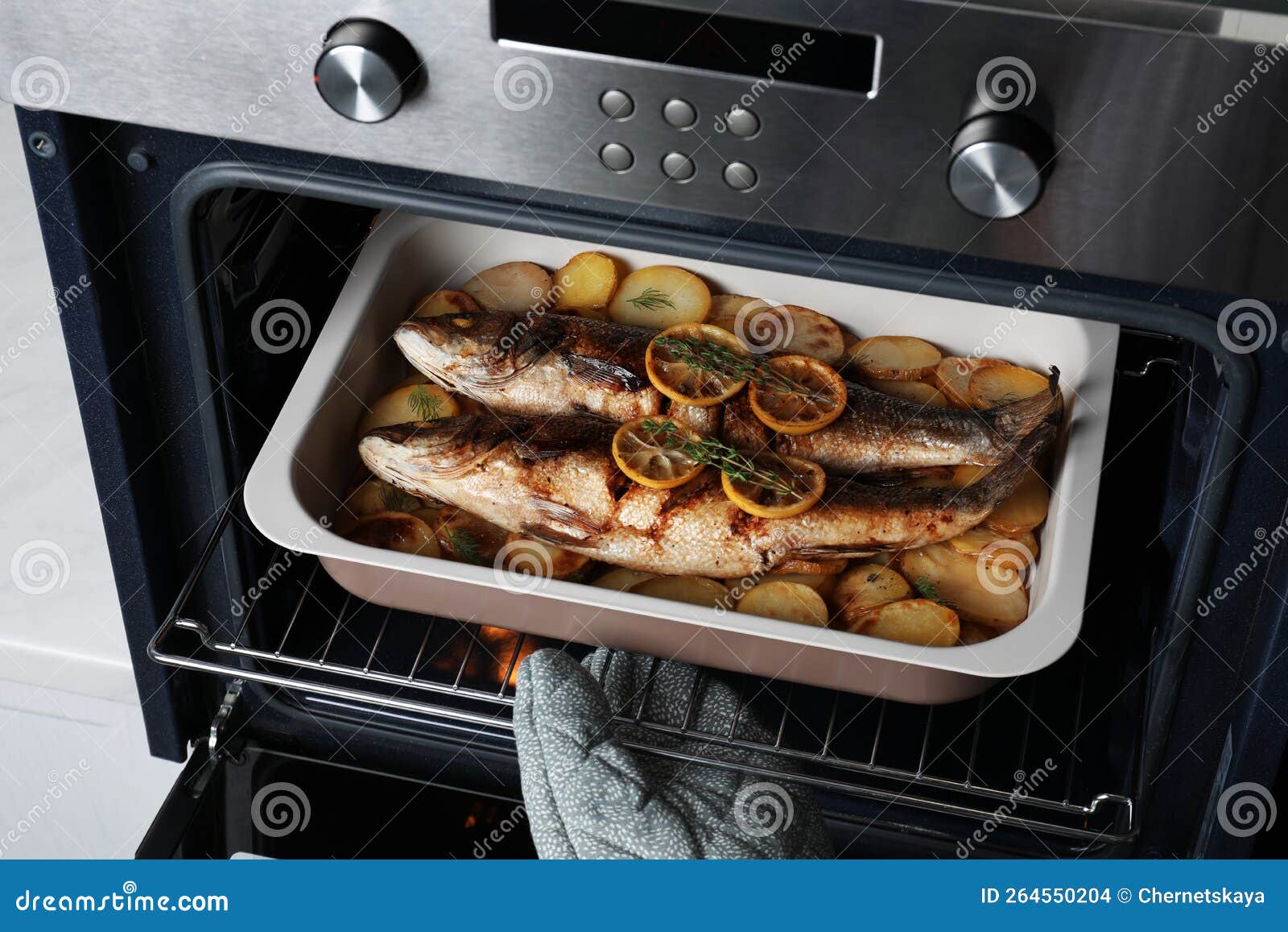 Frau, Die Mit Seebarsch-Fisch Und Kartoffeln Aus Dem Ofen Backen ...