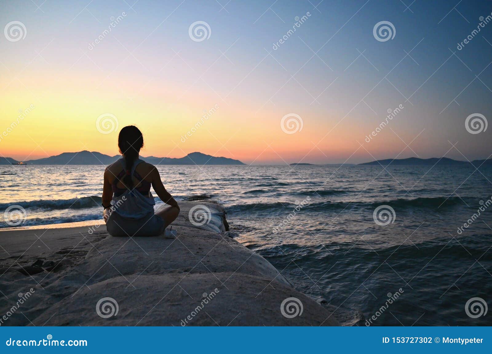 Frau meditiert - entspannt sich bei Sonnenuntergang durch das Meer auf dem Strand Konzept für Yoga, Gesundheit und Badekurort