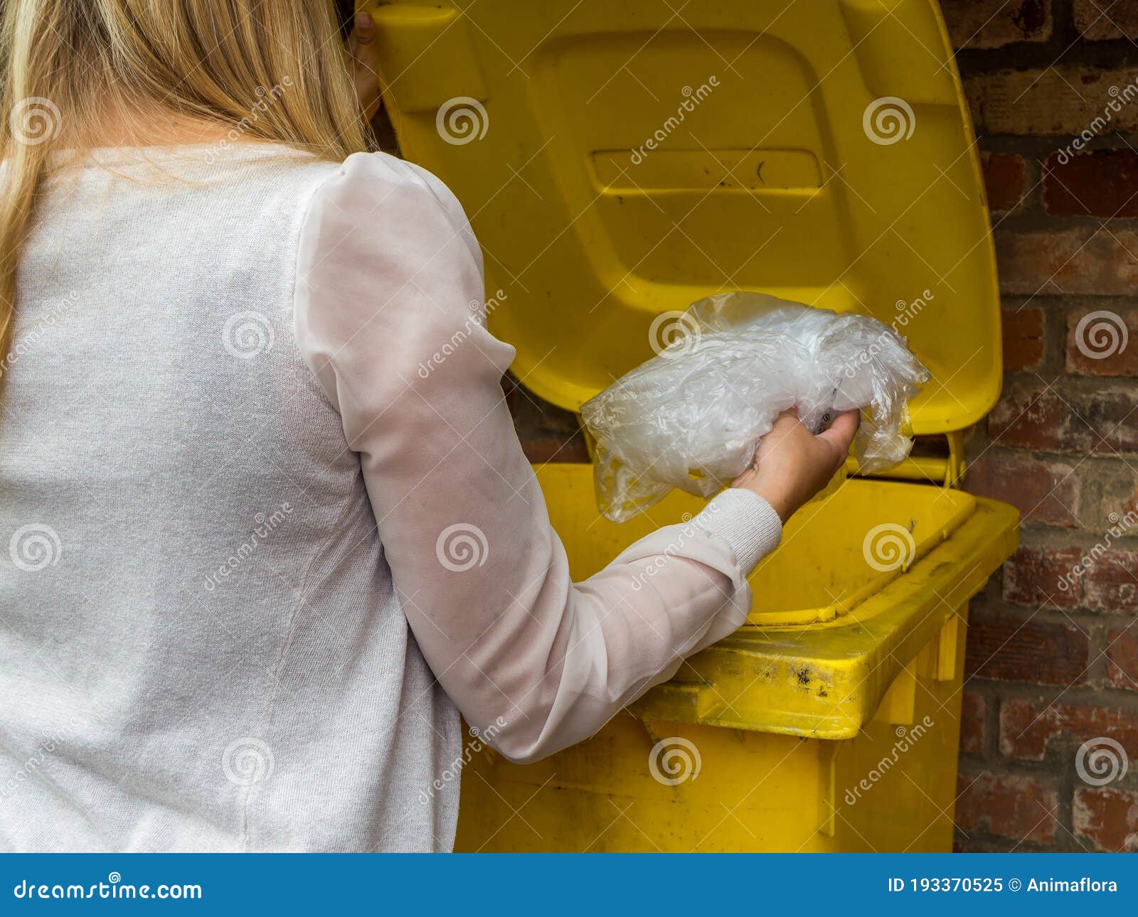 frau wirft etwas in gelbe tonne