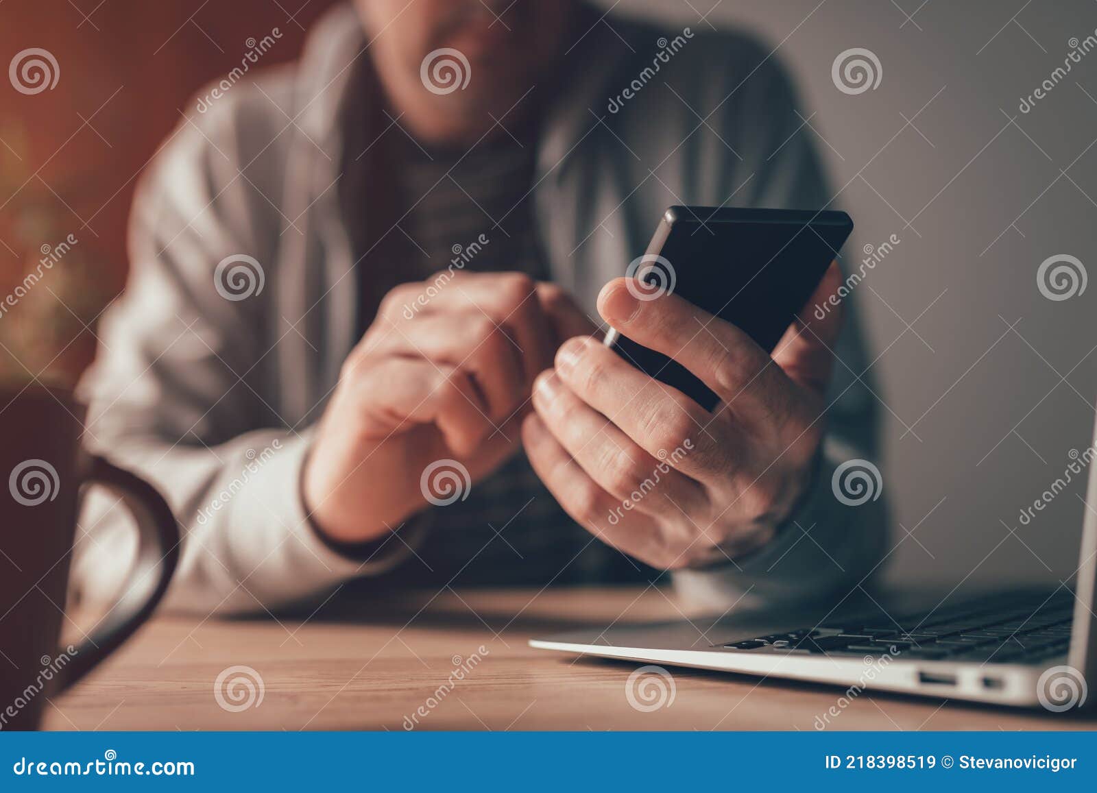 freelance worker typing text message on mobile smart phone at home office desk