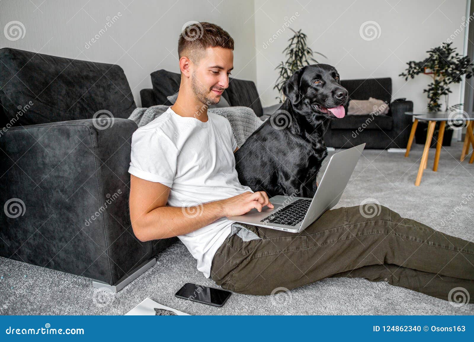 freelancer guy sitting at home working in laptop and with dog in