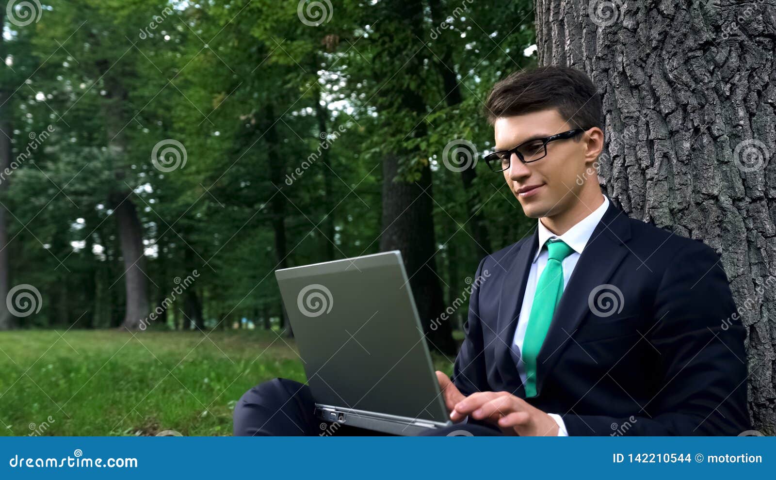 Freelancer Sitting Under Tree in Park and Using Laptop, Remote Work
