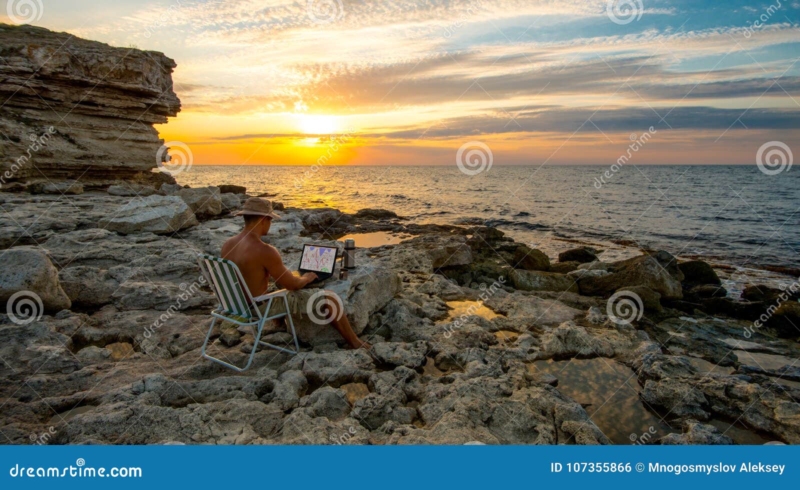 freelancer work on laptop on coast sea on deauty sunset background