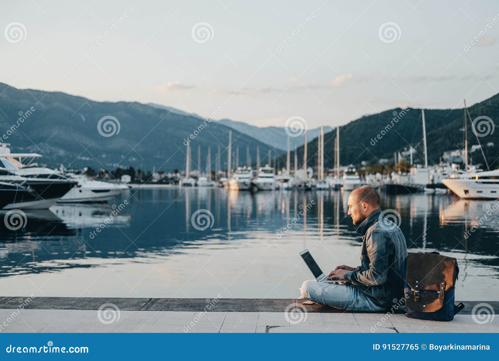 freelancer working on laptop on the shore near the yacht boat at