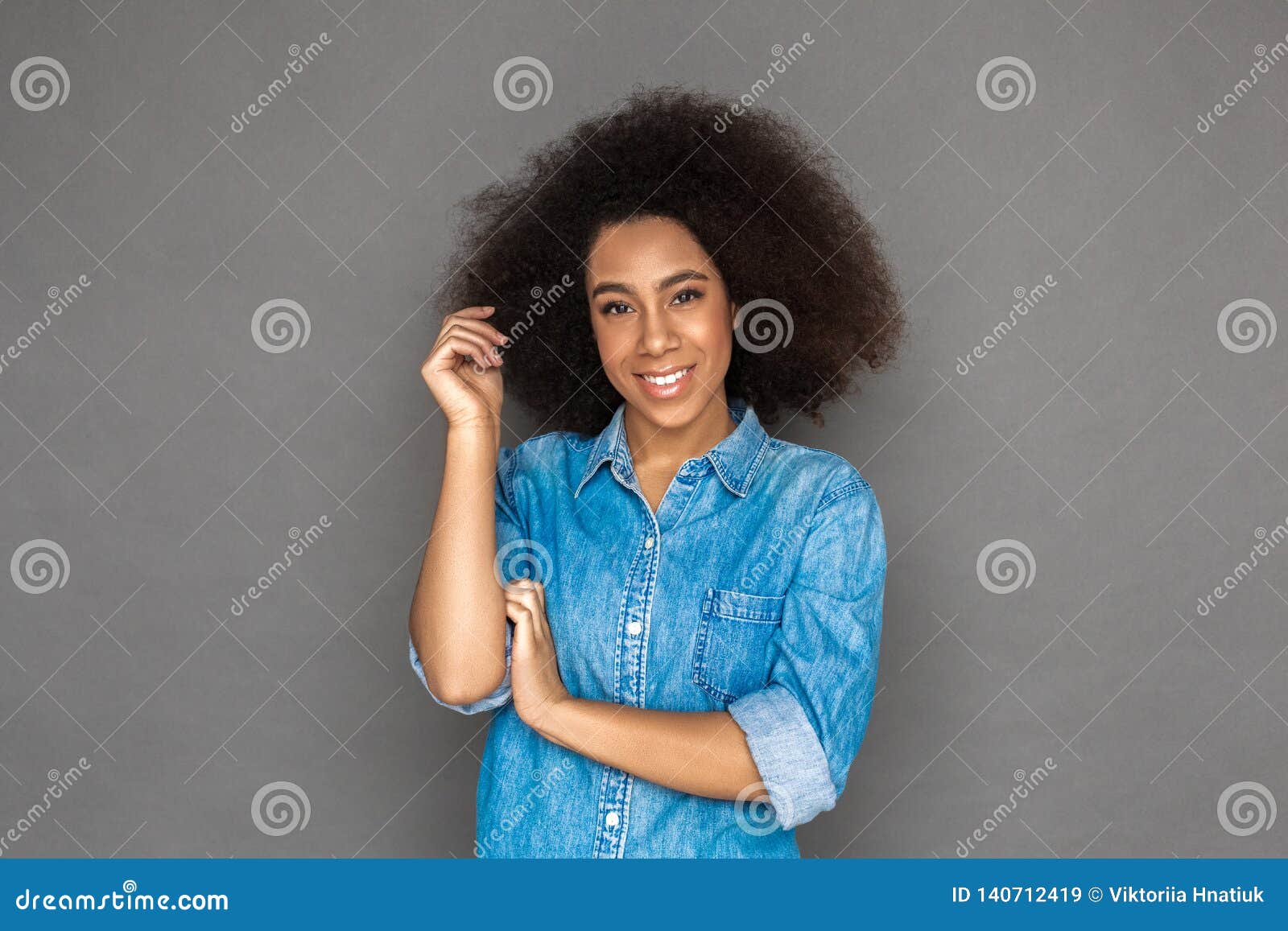 Freestyle Mulatto Woman Standing Isolated On Grey Touching Curl 