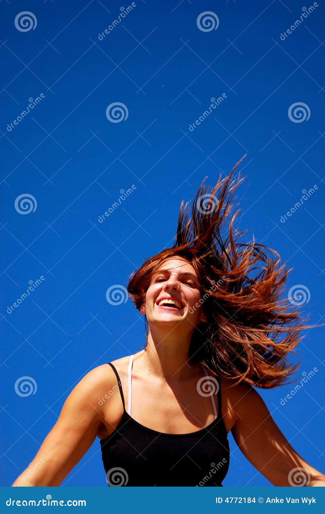 Frei glauben. Im Freienportrait einer attraktiven kaukasischen weißen Jugendlichen mit dem wilden Brunettehaar und glücklichen lächelnden Gesichtsdem ausdruck, die frei vor Hintergrund des blauen Himmels glaubt