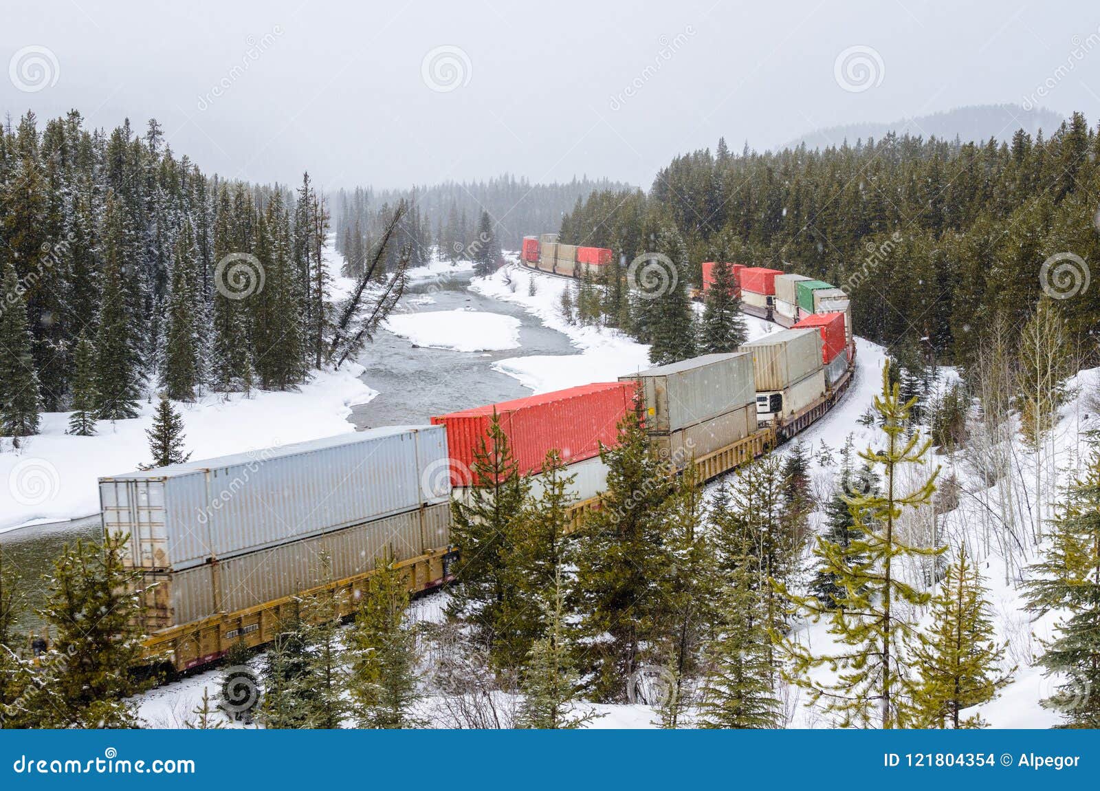 freight trainrunning alongside a river during a heavy snowfall