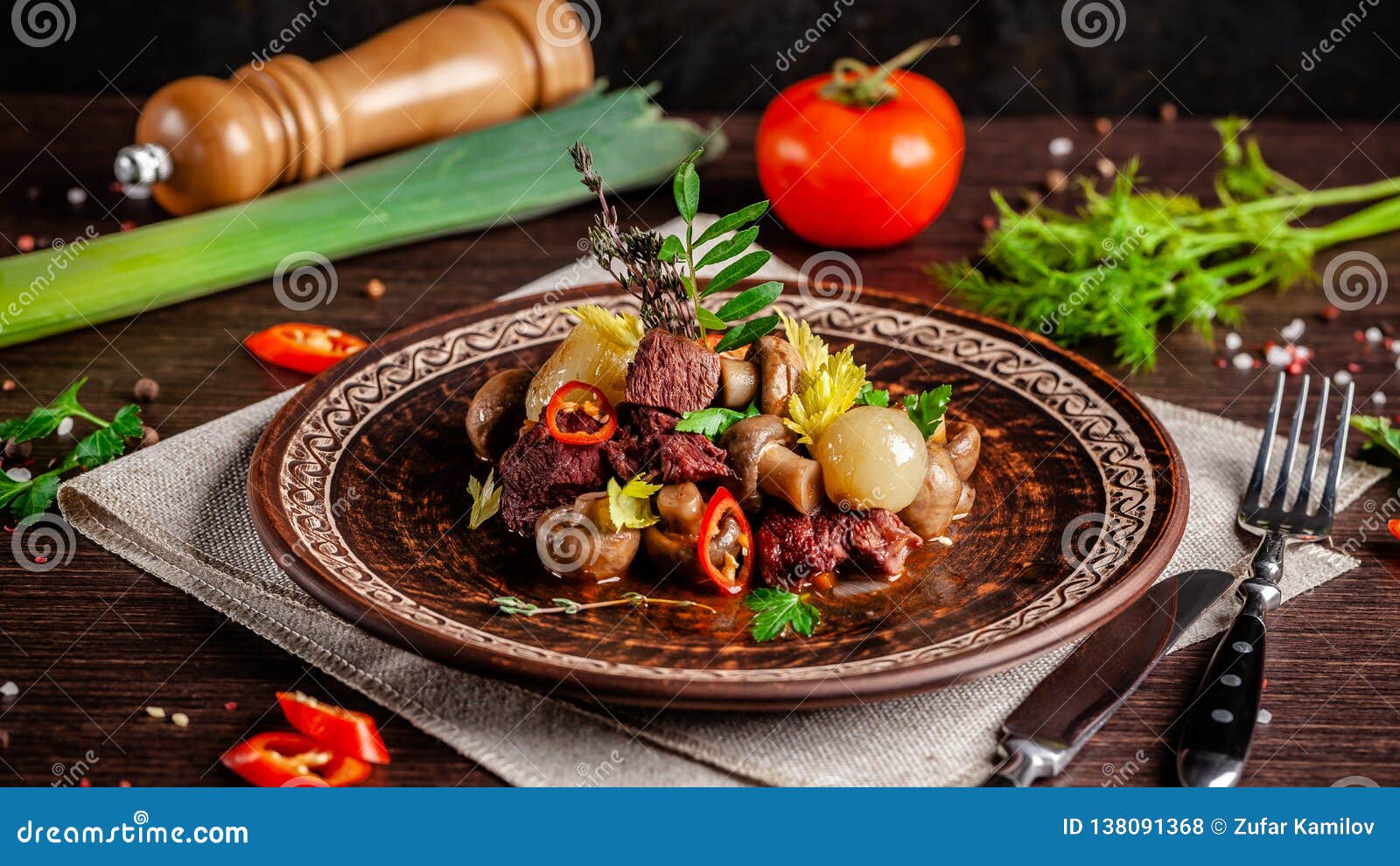 french cuisine concept. blanquette of veal with mushrooms, whole stewed onions, carrots and chilli peppers. serving dishes