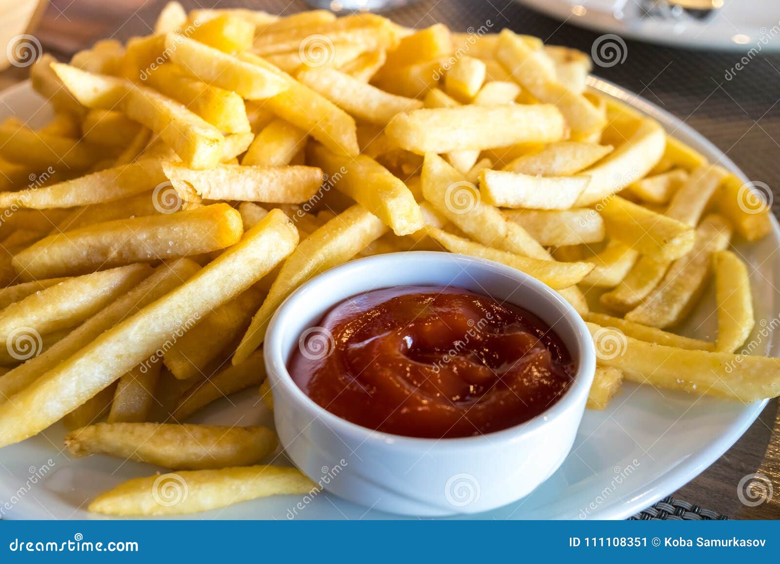 French Fries In A White Plate And Ketchup On A Table Stock Image