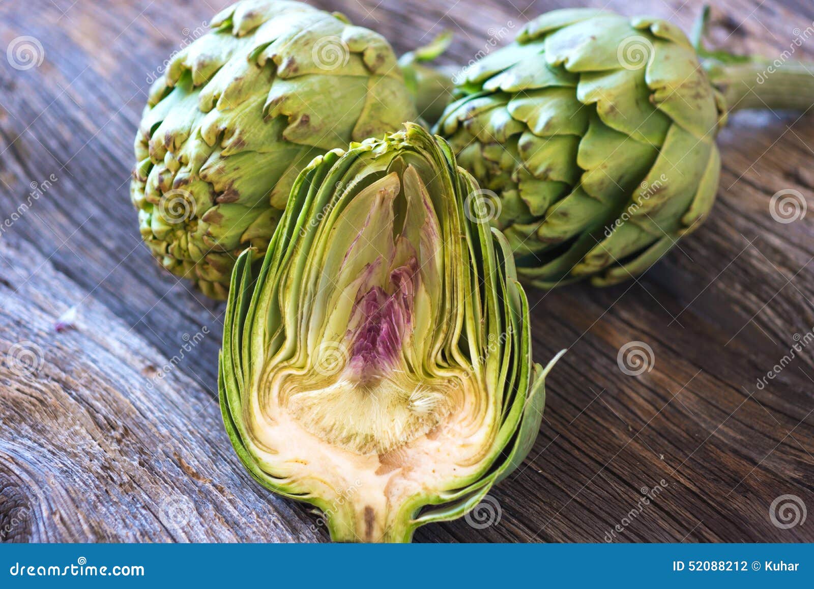 Fresh artichokes on rustic old wooden table.