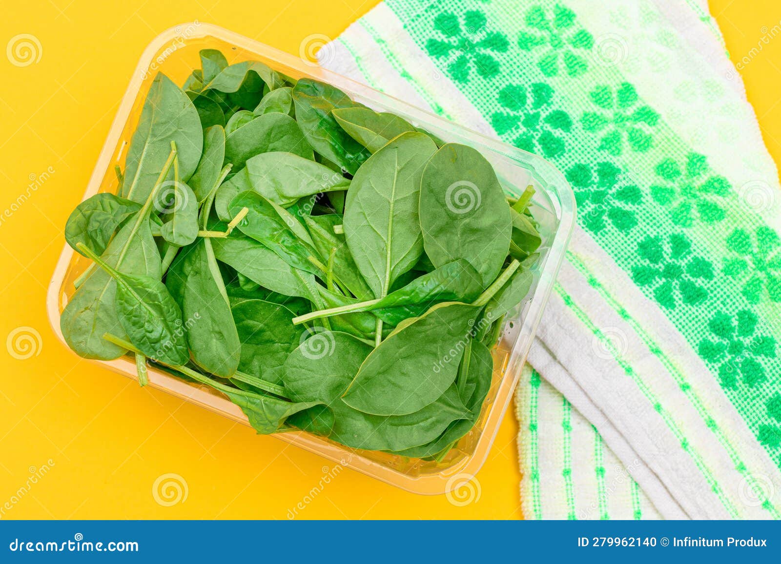 Fresh Baby Spinach Leaves in Transparent Plastic Package on Yellow