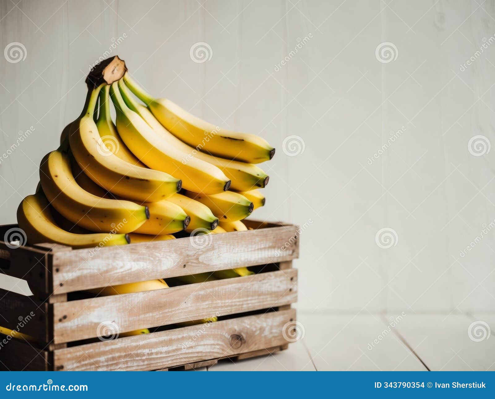 fresh bananas in a wooden crate on a light background.