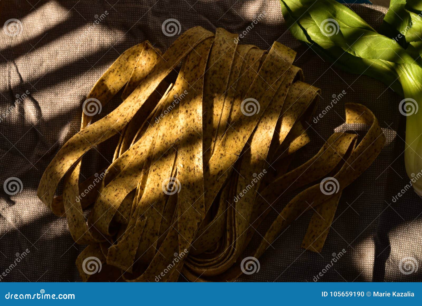 Fresh Basil Pasta Noodles in Shadow and Sunlight Pattern Stock Photo