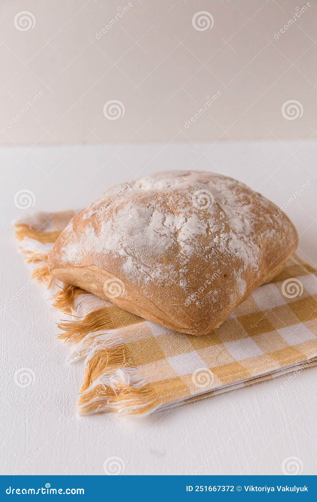 fresh chabata bread on a yellow towel on a white background