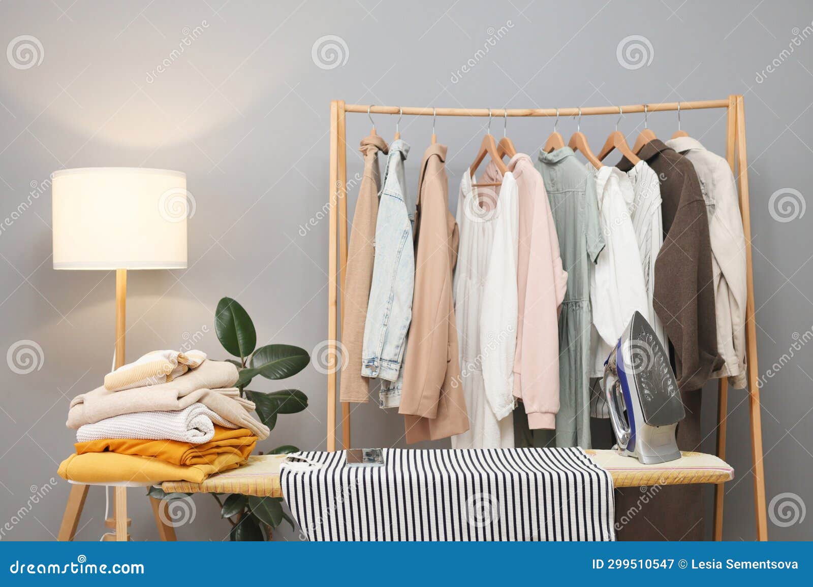 Fresh Clothes on Hangers and on Ironing Board Empty Working Space for Ironing Clothing at Home