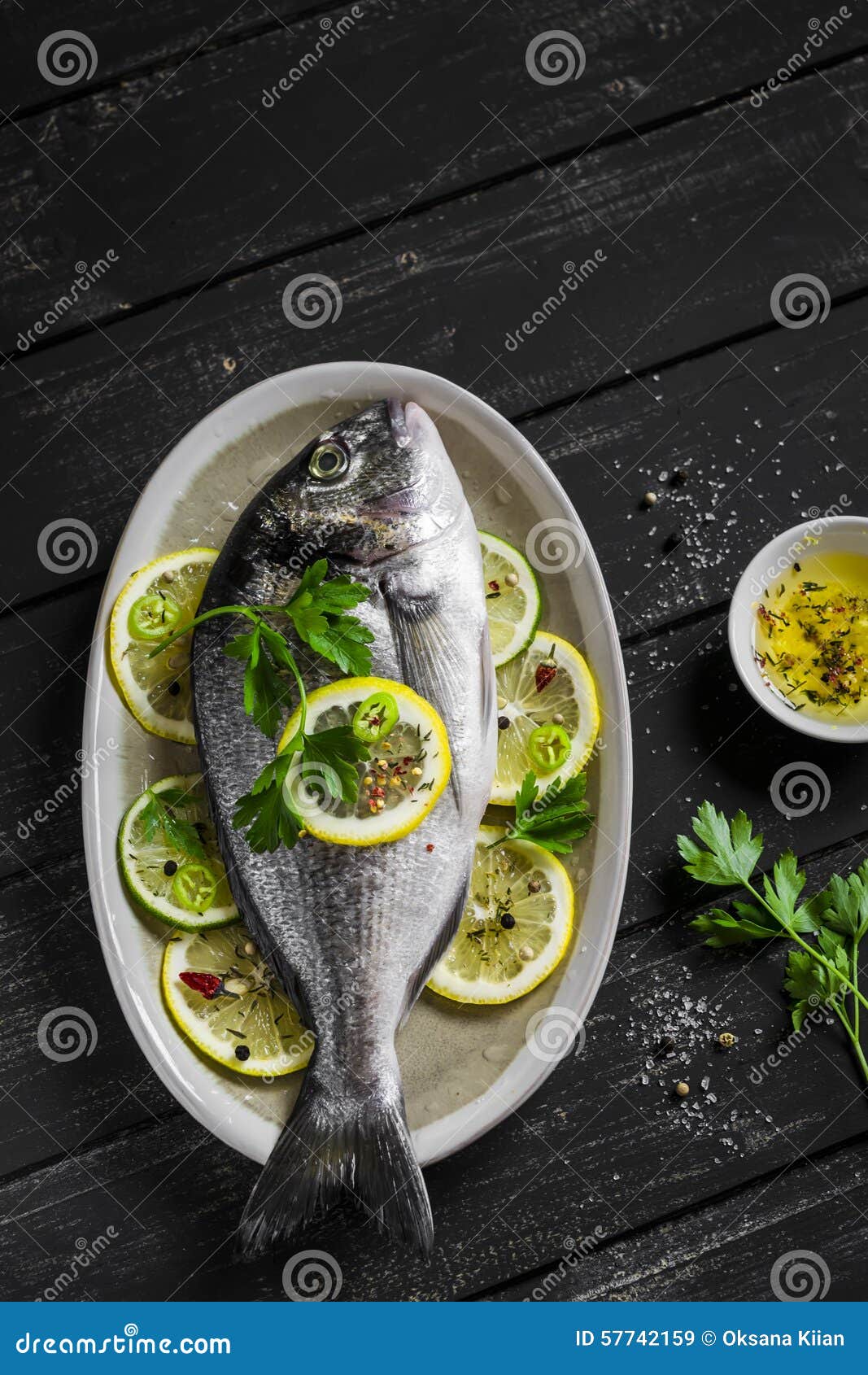 fresh dorado fish with lemon, lime and parsley on an oval dish