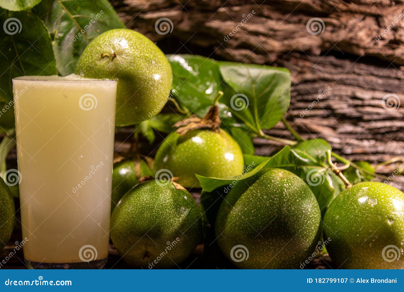 fresh fruits and glass of passion fruit passiflora edulis juice amid green leaves and wooden background