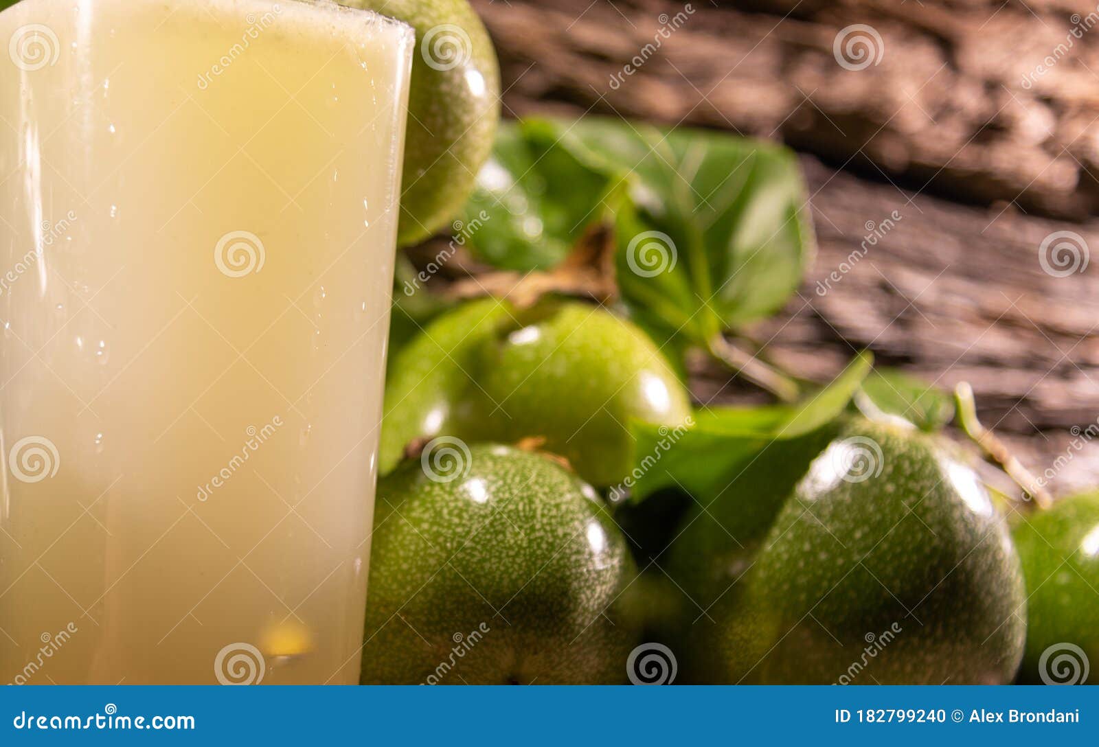 fresh fruits and glass of passion fruit passiflora edulis juice amid green leaves and wooden background