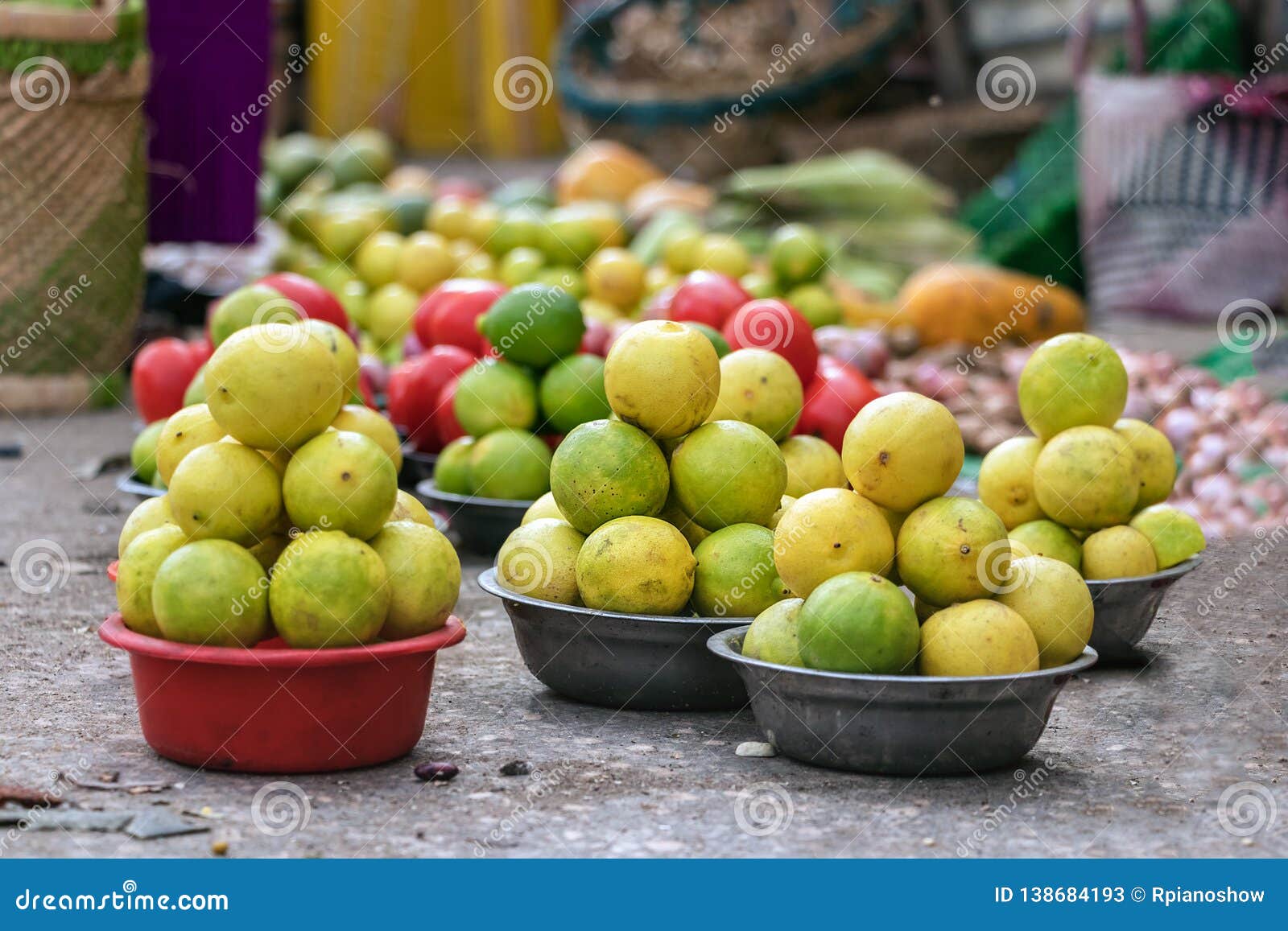 fresh green and yellow lemons placed on baskets on the floor at the street market of toliara, madagascar