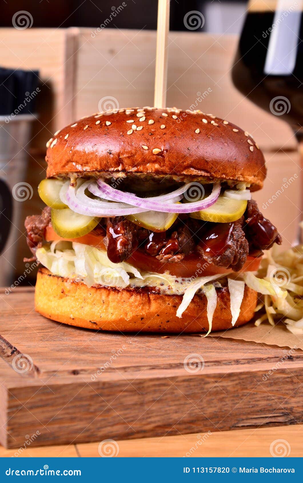 fresh homemade hamburger with beef, onion, sause and cabbage garnish on a wooden board, wooden table background. juicey