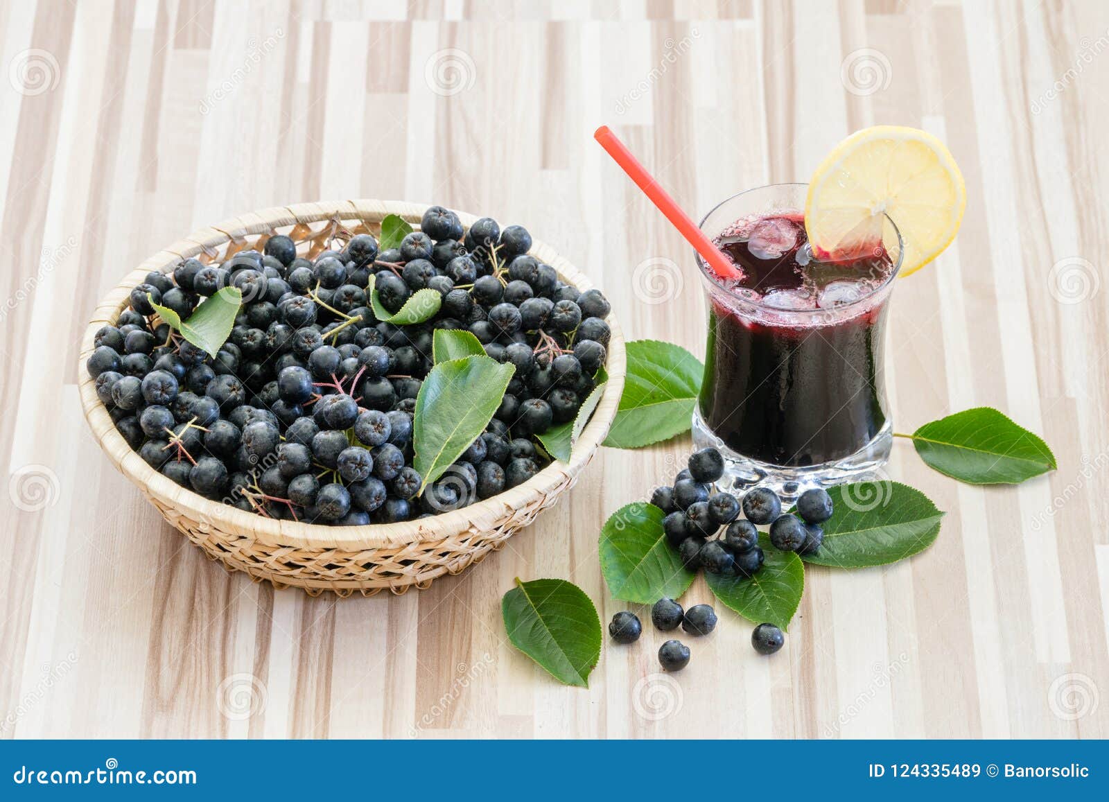 fresh juice of chokeberry or aronia melanocarpa in glass with ice, lemon and straw.