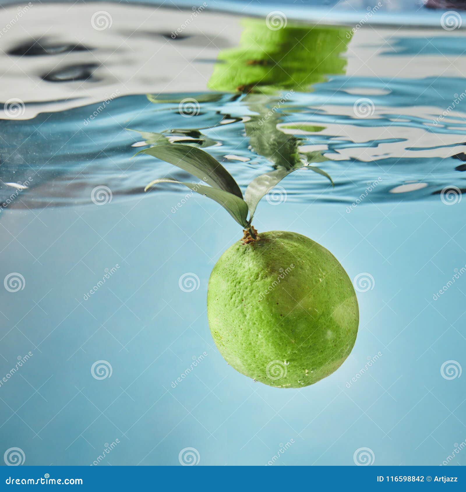 Fresh Lime Dropped into Water with Splash Isolated on Blue Stock Photo ...