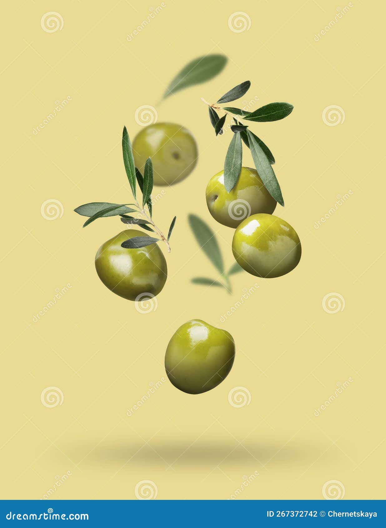 Fresh Olives and Leaves Falling on Pale Yellow Background Stock Photo