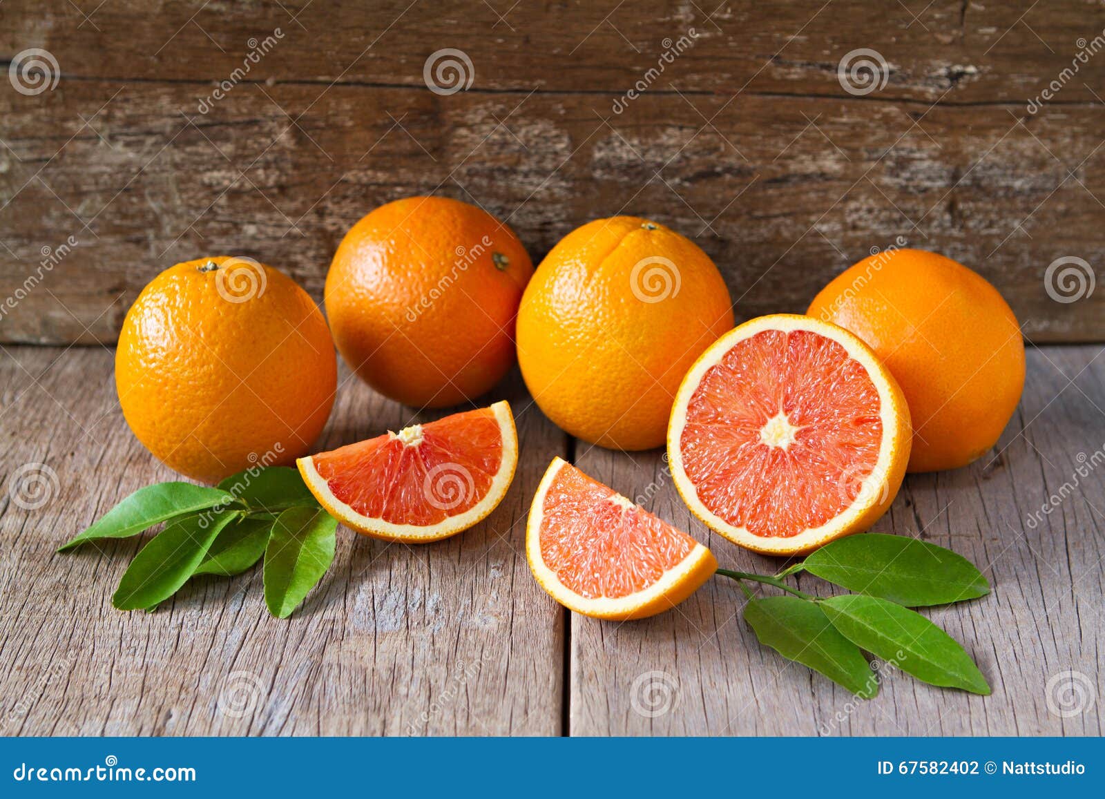 fresh oranges with slices and leaves on wooden background.