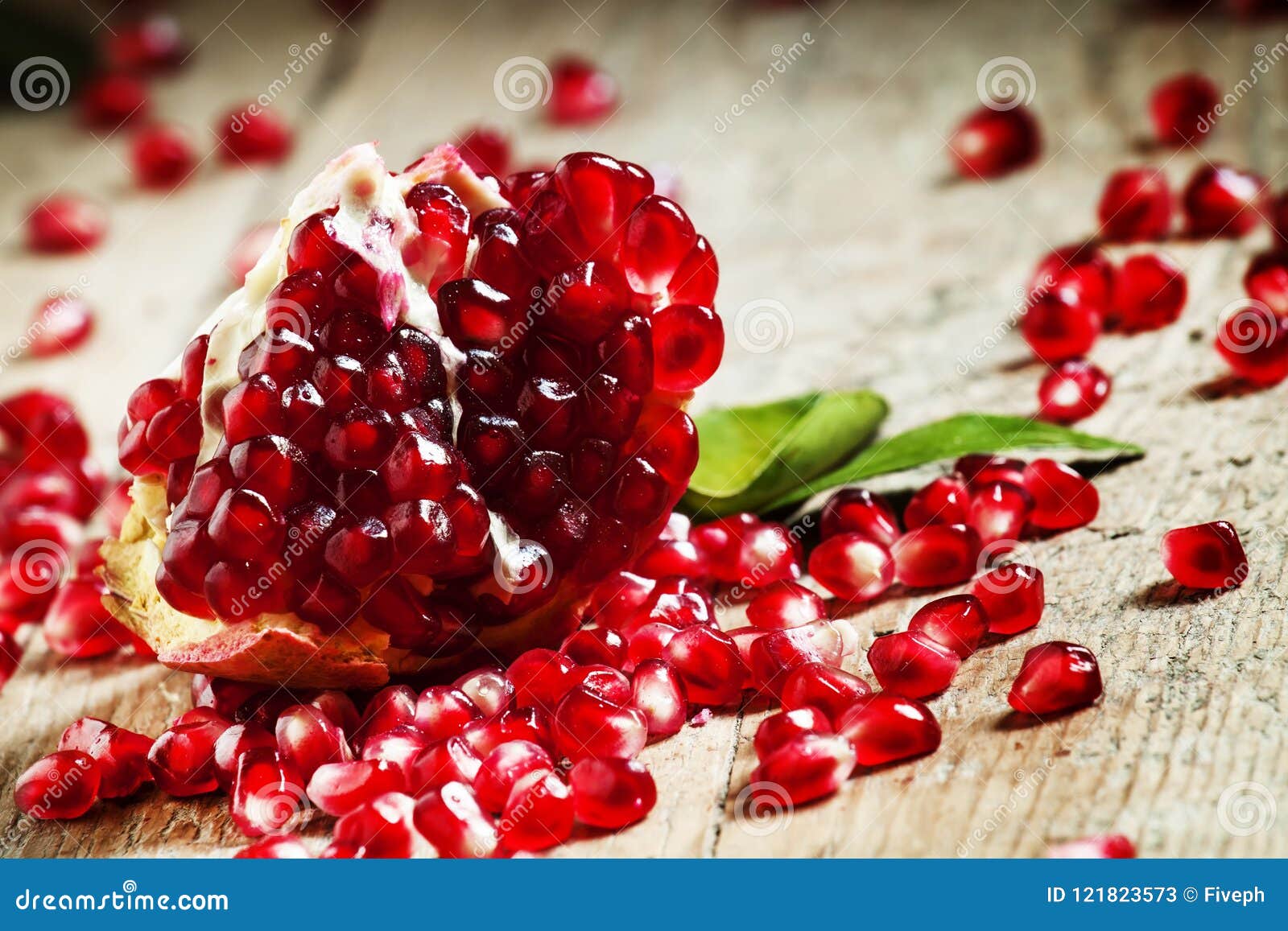 fresh peeled pomegranates with ruby red beans on old wooden table, selective focus