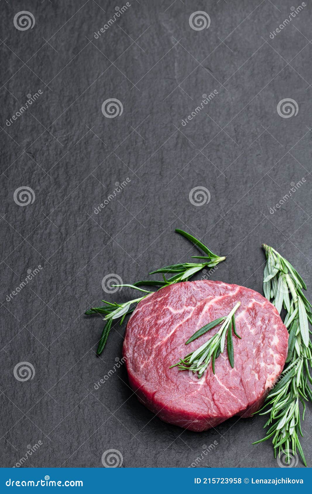 Fresh Raw Beef Steak with Rosemary Stick on Black Stone Background