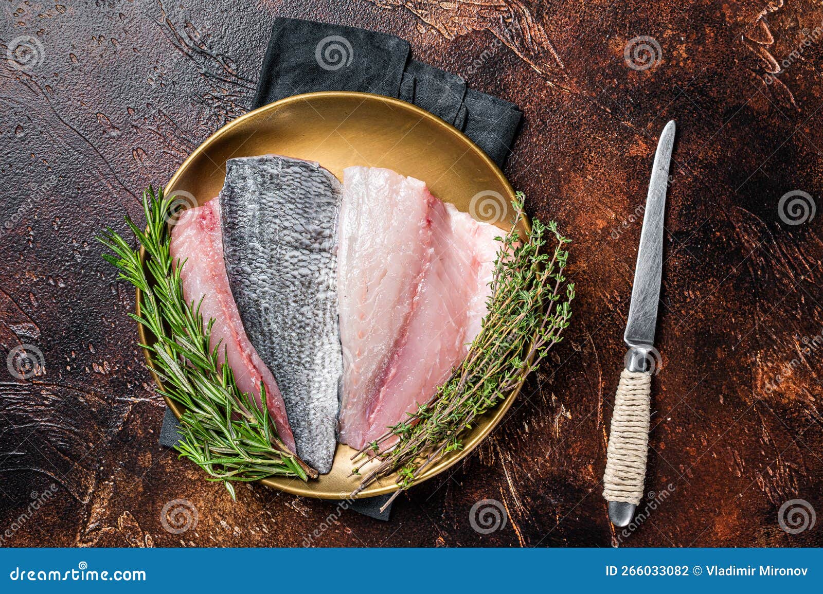 fresh raw gilthead sea bream fish fillets ready for cooking. dark background. top view