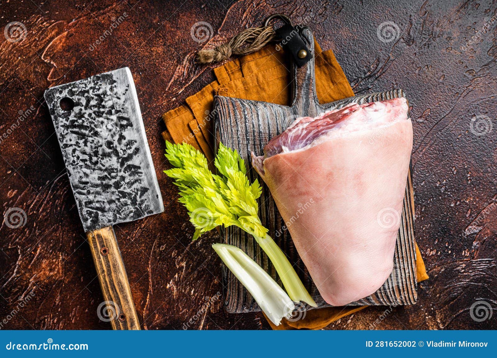 fresh raw pork shank knuckle on a butcher board with herbs for cooking. dark background. top view