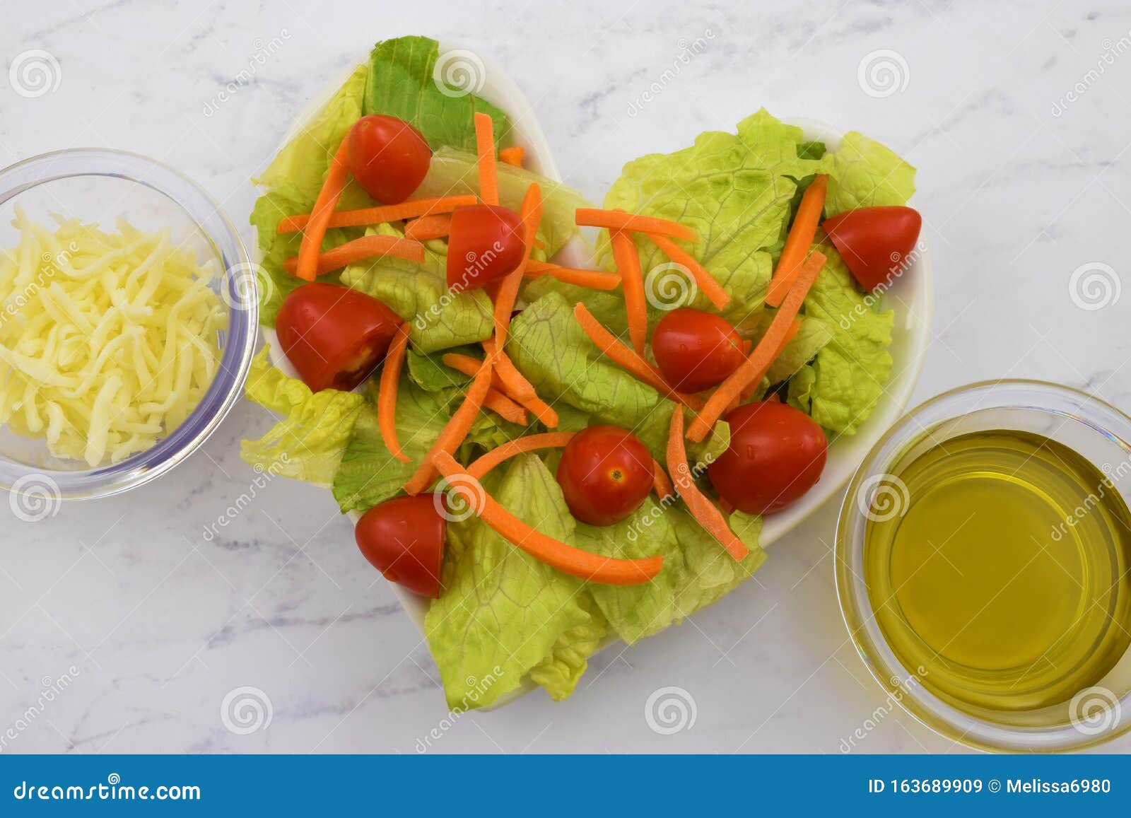 fresh heart healthy salad featuring tomatoes, carrots and romaine lettuce. adorned with olive oil & cheese toppings.